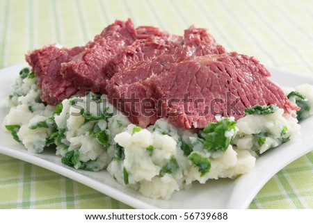 Slices of corned beef on top of colcannon (mashed potatoes with kale).
