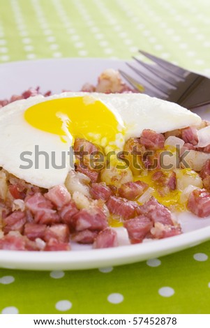 Corned beef fried with potatoes and onions, topped with a partially eaten runny sunny side up egg.