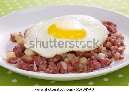 Corned beef fried with potatoes and onions, topped with a sunny side up fried egg.