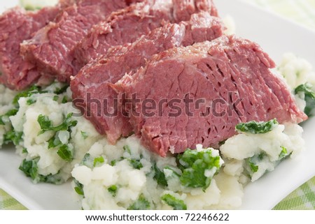 Slices of corned beef on top of colcannon (mashed potatoes with kale).