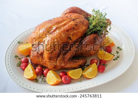 Christmas turkey on the big white plate with thyme, baby apples and oranges