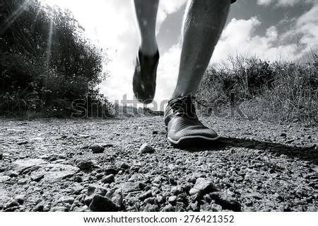 black and white photo of a runner running towards the camera on a gravel road