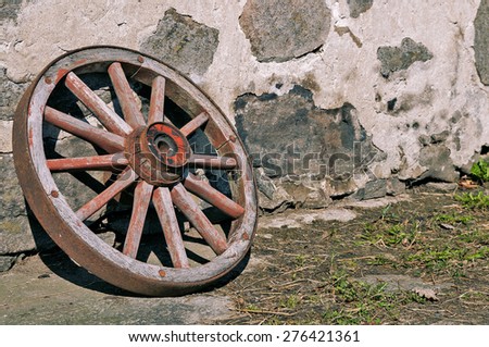 Old wooden wheel next to a stone wall