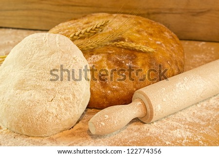 Freshly baked bread on wooden board with rolling pin