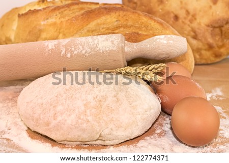 Still life with bread, dough, flour and rolling-pin on a wooden board