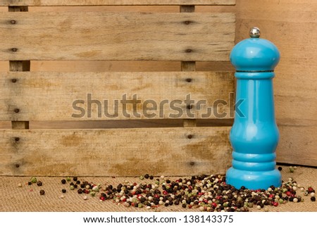Pepper and pepper mill over wooden background
