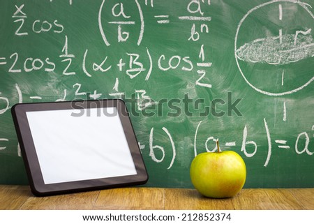 Tablet pc and apple over green  blackboard