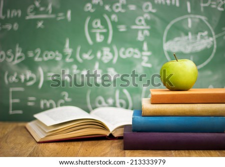 School books with apple on desk over green  school board background
