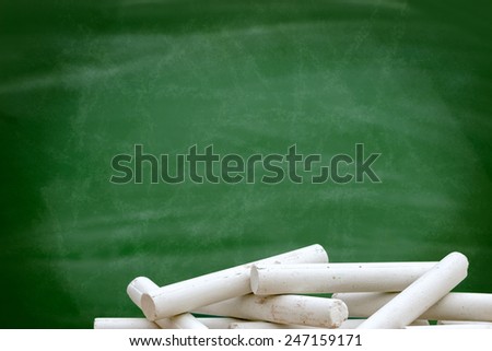 Pile of white chalk front of blackboard green,  empty blank with copy space for chalk text