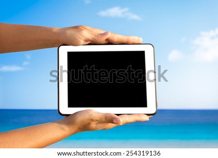 hands with digital tablet over great sea in the background, travel concept