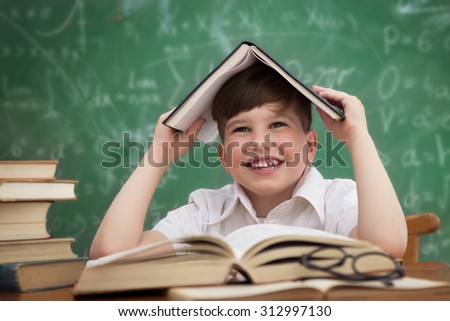 Happy little boy, pupil with book on head, education concept