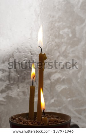 light on three candles on a background frozen window