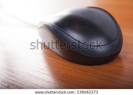 black mouse on wooden table highlights from monitor