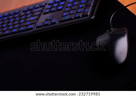 black keyboard  with light on keys and black mouse on black mat