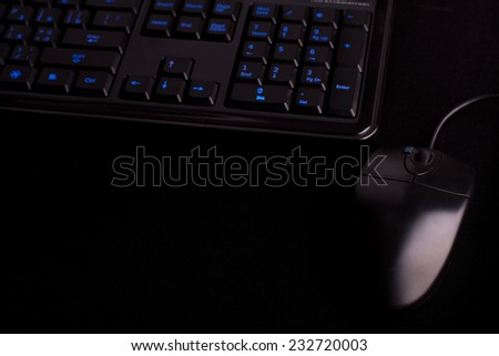 black keyboard  with light on keys and black mouse on black mat