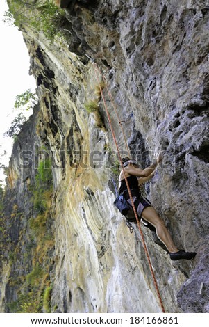 RAILAY, KRABI, THAILAND - MARCH 27: Rock climber ascends one of the popular climbing routes on March 27, 2014, at Railay Beach, Krabi, Thailand. Railay beach is a popular rock climbing location.