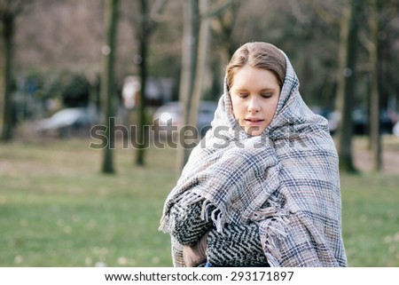 Woman wrapped in a blanket during a winter day in the park
