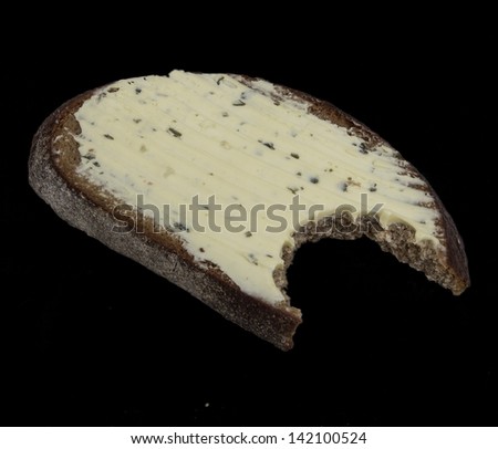 bitten bread and butter with seasonings on black background