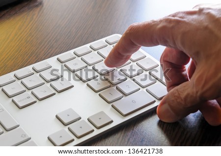 A senior man is using the numeric keyboard of his computer