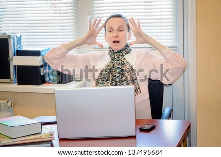 A fifty years old woman working in office with a laptop computer is very angry with the modern technology