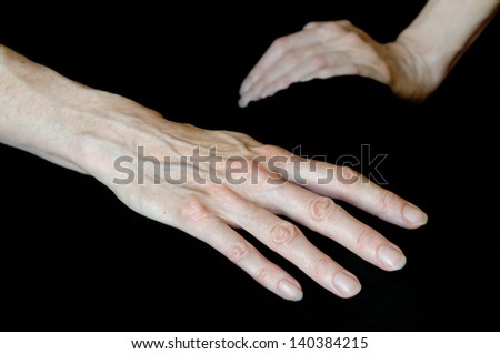Close up of senior woman\'s hands in different positions on black background. Here one open hand shows long fingers