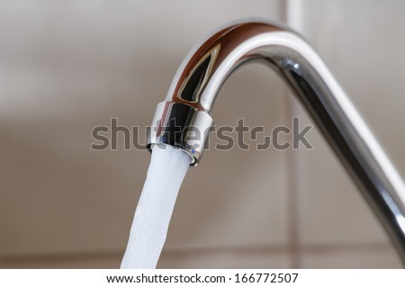 Horizontal image of a tap with water flowing strongly under high pressure