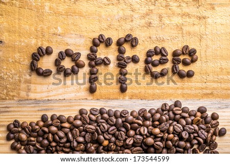 Light wood background texture with coffee beans writing the word 
