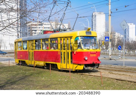 KIEV, UKRAINE - MARCH 30, 2010 - A yellow and red tramway in the Timoshemko boulevard. People cross the tram tracks for the tram route number 16 in Kiev Obolon quarter.