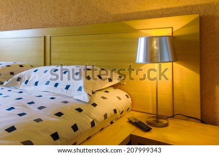 Detail of a bed with a lighten bedside lamp