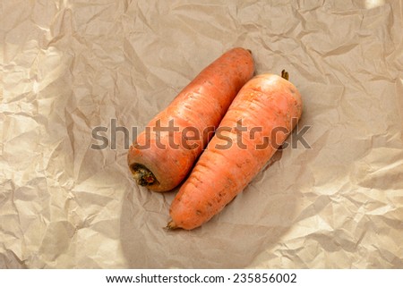 Two nice natural carrots on a brown piece of craft paper