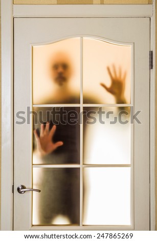 Silhouette of an unknown man in black  seen behind a closed glass door, like a ghost or an alien
