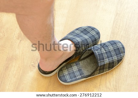 A pair of warm slippers with a man\'s leg