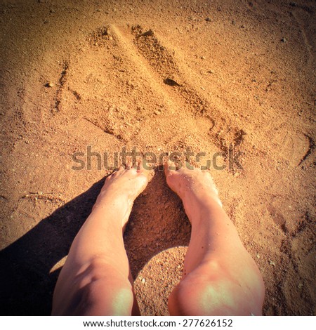 Vintage image of woman\'s feet in the warm yellow sand, with instagram effect, and room for copy text