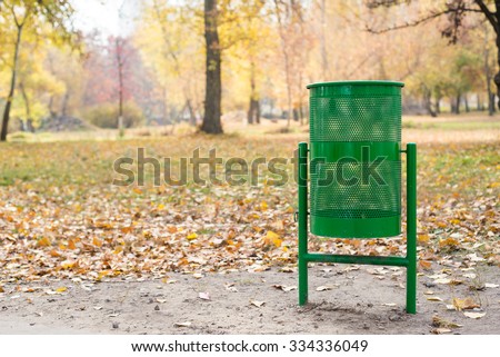 New green trash bin in the park in autumn