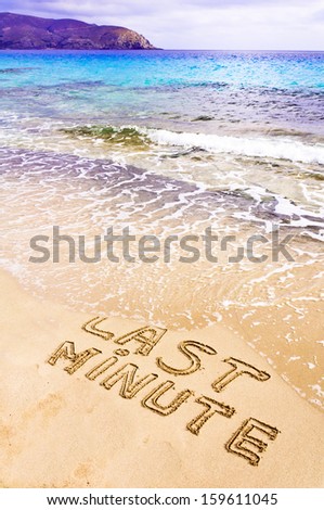 Last Minute written on sand, being washed away by waves, vacation concept