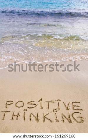 Positive Thinking message written on sand, with waves in background
