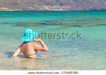 Beautiful young woman in swimsuit with sunhat, relaxing on the sunny beach. Chill out concept
