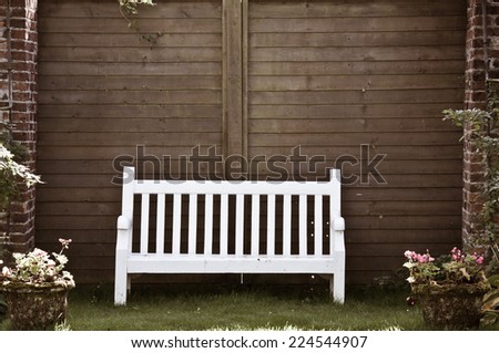 White Wooden garden bench in English garden, retro color filter applied