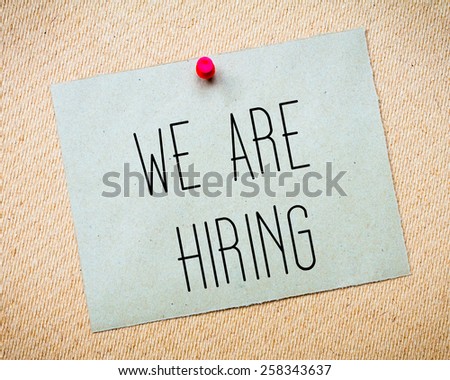 Recycled paper note pinned on cork board.We are hiring Message. Concept Image