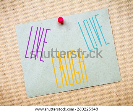 Recycled paper note pinned on cork board. Live Laugh Love Message. Concept Image