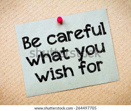 Be careful what you wish for Message. Recycled paper note pinned on cork board. Concept Image