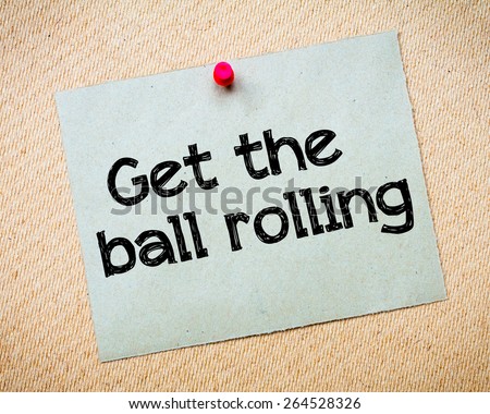 Get the ball rolling Message. Recycled paper note pinned on cork board. Concept Image