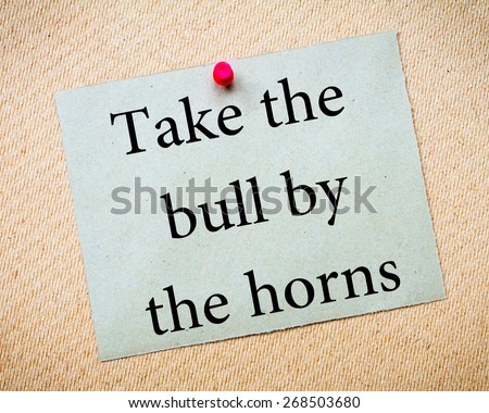 Take The Bull By The Horns Message. Recycled paper note pinned on cork board. Concept Image