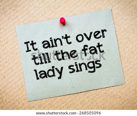 It ain\'t over till the fat lady sings Message. Recycled paper note pinned on cork board. Concept Image