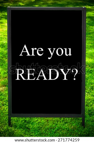 ARE YOU READY?  message on sidewalk blackboard sign against green grass background. Copy Space available. Concept image