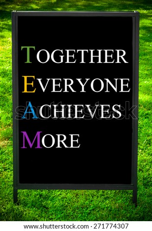 TOGETHER EVERYONE ACHIEVES MORE  message on sidewalk blackboard sign against green grass background. Copy Space available. Concept image
