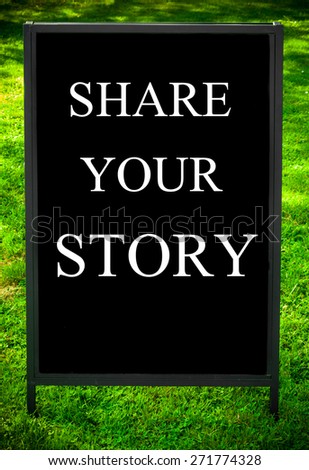 SHARE YOUR STORY  message on sidewalk blackboard sign against green grass background. Copy Space available. Concept image