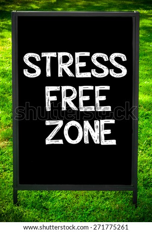 STRESS FREE ZONE  message on sidewalk blackboard sign against green grass background. Copy Space available. Concept image