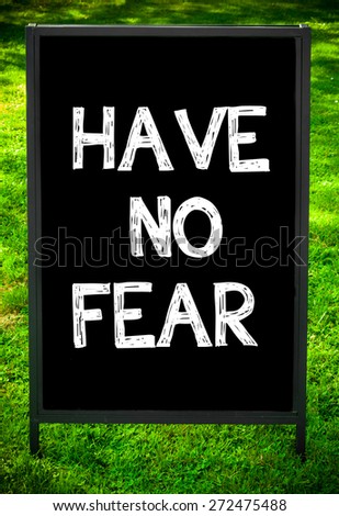 HAVE NO FEAR  message on sidewalk blackboard sign against green grass background. Copy Space available. Concept image