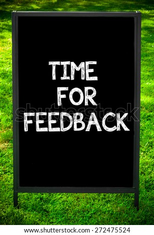 TIME FOR FEEDBACK  message on sidewalk blackboard sign against green grass background. Copy Space available. Concept image